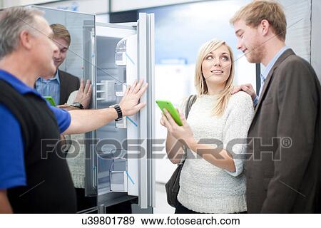 Young couple looking at fridge in showroom View Large Photo Image Stock Photo - Young couple looking at fridge in showroom. Fotosearch
