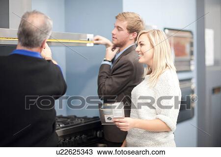Young couple looking at ovens in showroom View Large Photo Image Stock Image - Young couple looking at ovens in showroom. Fotosearch
