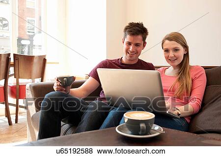 Young couple looking at personal computer in cafe View Large Photo Image Stock Photo - Young couple looking at personal computer in cafe. Fotosearch