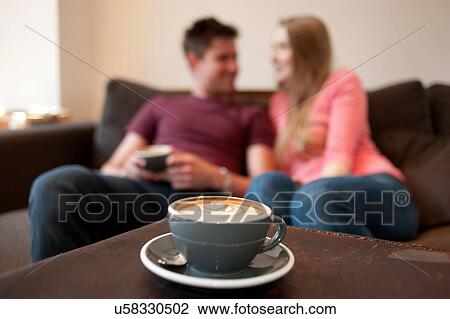 Stock Image - Young couple lounging on sofa in cafe. Fotosearch