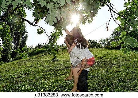 Young couple reaching up to tree branches View Large Photo Image Stock Image - Young couple reaching up to tree branches. Fotosearch