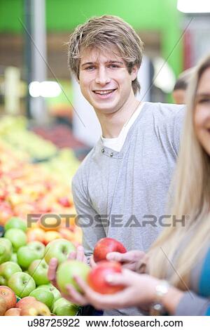 Young couple with apples in indoor market View Large Photo Image Stock Image - Young couple with apples in indoor market. Fotosearch