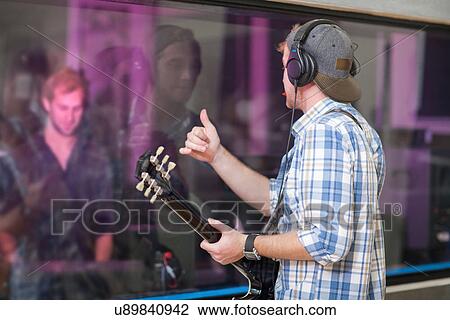 Stock Image - Young guitarist in recording studio. Fotosearch