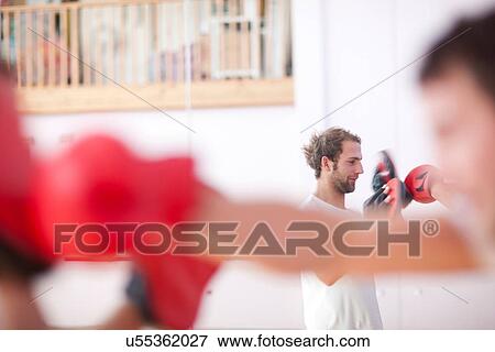 Young man and trainer boxing in gym View Large Photo Image Stock Photo - Young man and trainer boxing in gym. Fotosearch