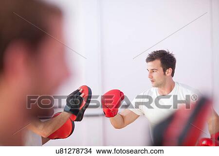 Picture - Young man and trainer boxing in sports hall. Fotosearch