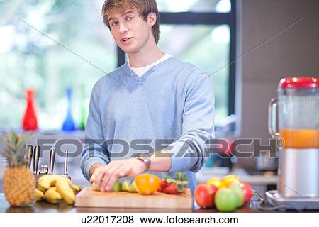Young man in kitchen preparing fruit drink View Large Photo Image Stock Photo - Young man in kitchen preparing fruit drink. Fotosearch