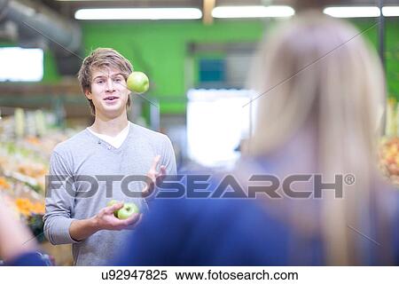 Young man juggling apples in indoor market View Large Photo Image Stock Photography - Young man juggling apples in indoor market. Fotosearch