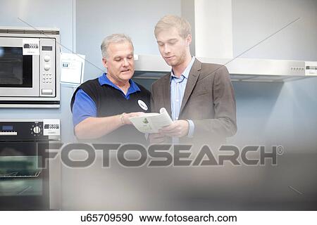 Young man looking at appliance brochure in showroom View Large Photo Image Stock Image - Young man looking at appliance brochure in showroom. Fotosearch
