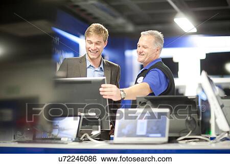 Stock Photograph - Young man looking at computers in showroom. Fotosearch
