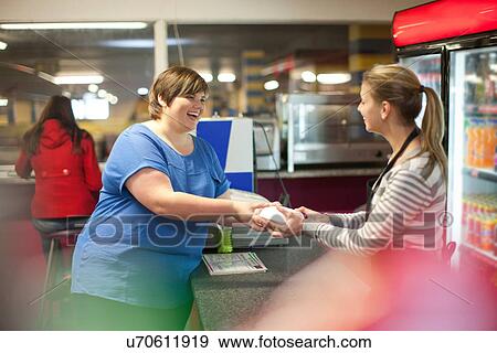 Stock Photo - Young woman collecting takeaway order in cafe. Fotosearch