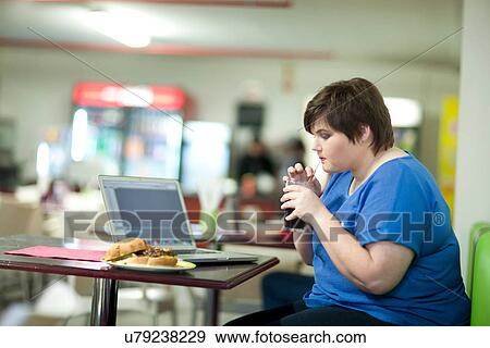 Stock Photo - Young woman drinking coke in cafe. Fotosearch