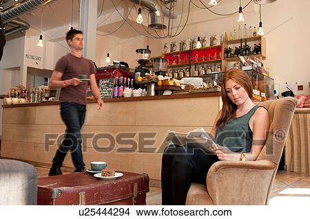 Young woman having tea and reading newspaper in cafe View Large Photo Image Picture - Young woman having tea and reading newspaper in cafe. Fotosearch