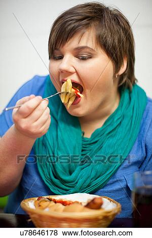 Stock Photo - Young woman in cafe eating fries. Fotosearch