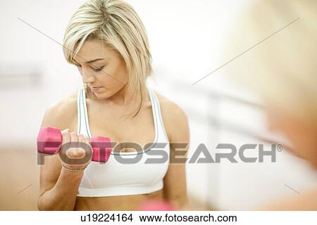 Young woman in gym training with dumbbells View Large Photo Image Picture - Young woman in gym training with dumbbells. Fotosearch