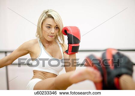 Stock Photograph - Young woman kickboxing in gym. Fotosearch
