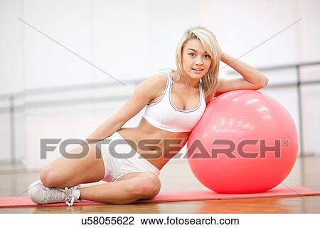 Young woman leaning on exercise ball in aerobics class View Large Photo Image Stock Image - Young woman leaning on exercise ball in aerobics class. Fotosearch