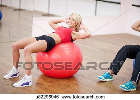 Young woman lying on exercise ball in aerobics class View Large Photo Image Stock Photograph - Young woman lying on exercise ball in aerobics class. Fotosearch