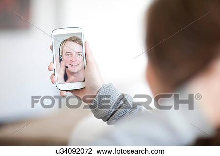 Young woman making video call on cellphone View Large Photo Image Stock Image - Young woman making video call on cellphone. Fotosearch