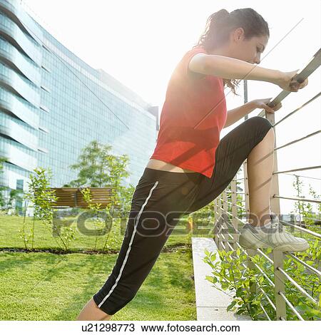 Stock Image - Young woman runner stretching. Fotosearch