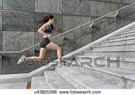 Young woman running up stairway View Large Photo Image Stock Photo - Young woman running up stairway. Fotosearch