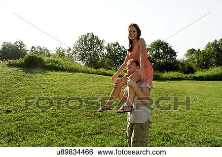 Young woman sitting on young mans shoulders View Large Photo Image Stock Photograph - Young woman sitting on young mans shoulders. Fotosearch