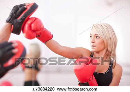 Stock Image - Young woman training in boxing gloves. Fotosearch
