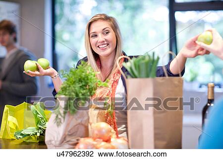 Stock Image - Young woman unpacking groceries. Fotosearch
