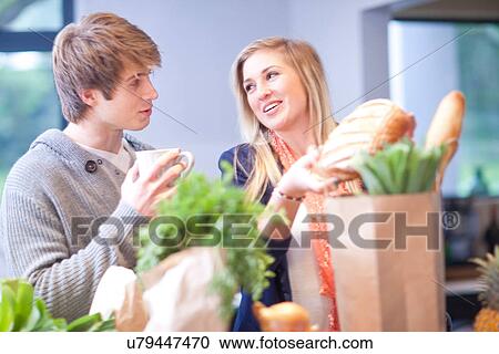 Stock Image - Young woman unpacking shopping. Fotosearch
