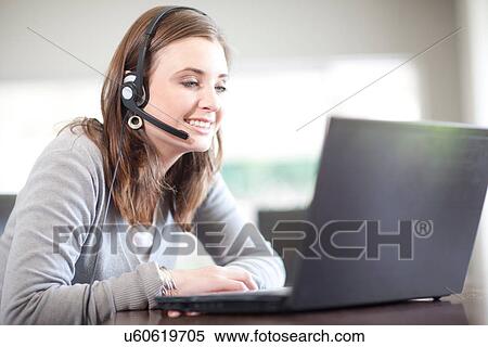 Young woman wearing headset using computer View Large Photo Image Stock Photography - Young woman wearing headset using computer. Fotosearch