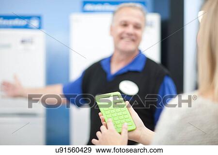 Stock Photo - Young woman with calculator in showroom. Fotosearch