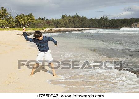 Stock Image - Boy (10-11) playing on beach. Fotosearch