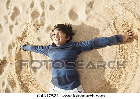 Stock Image - Boy (10-11) playing on beach. Fotosearch