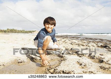 Boy (10-11) playing on beach View Large Photo Image Stock Image - Boy (10-11) playing on beach. Fotosearch