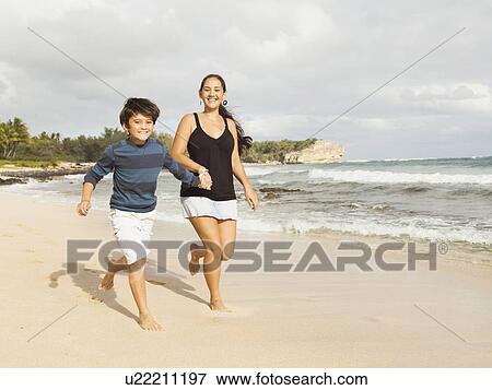 Boy (10-11) running on beach with mother View Large Photo Image Stock Photo - Boy (10-11) running on beach with mother. Fotosearch