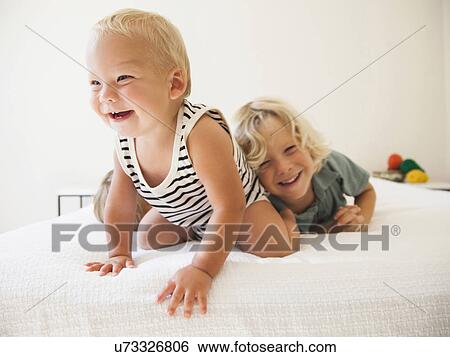 Stock Photograph - Boy (6-7) and girl (2-3) playing with their baby brother (6-11 months). Fotosearch
