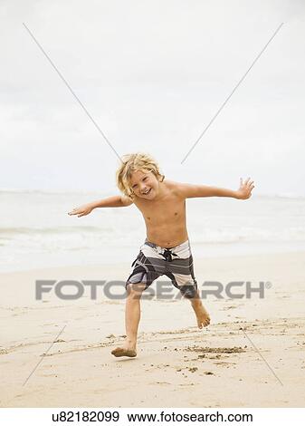 Stock Photo - Boy (6-7) playing on beach. Fotosearch