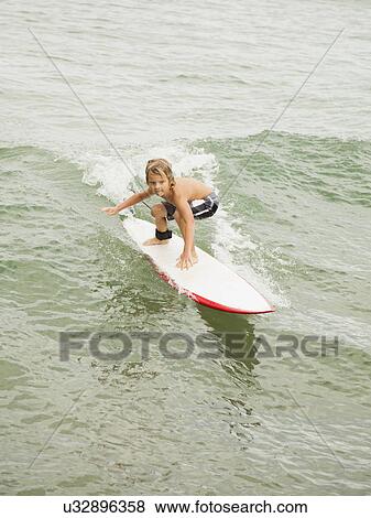 Boy (6-7) surfing View Large Photo Image Stock Photo - Boy (6-7) surfing. Fotosearch