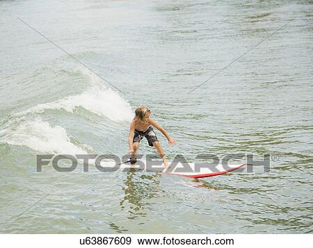 Boy (6-7) surfing View Large Photo Image Stock Photo - Boy (6-7) surfing. Fotosearch