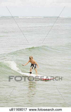 Boy (6-7) surfing View Large Photo Image Stock Photo - Boy (6-7) surfing. Fotosearch