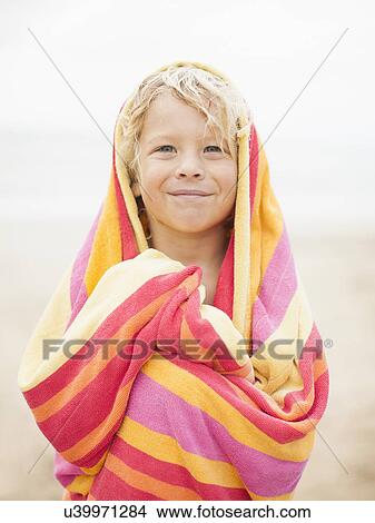 Picture - Boy (6-7) wrapped in towel on beach. Fotosearch