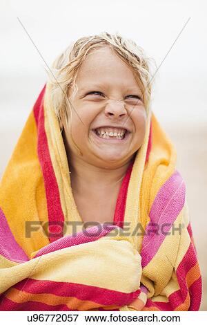 Stock Photo - Boy (6-7) wrapped in towel on beach. Fotosearch