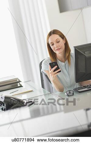 Business woman using computer and phone in office View Large Photo Image Picture - Business woman using computer and phone in office. Fotosearch