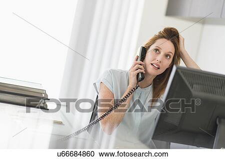 Business woman using computer and phone in office View Large Photo Image Stock Image - Business woman using computer and phone in office. Fotosearch