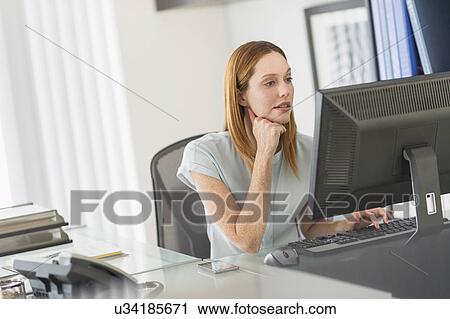 Stock Image - Business woman using computer in office. Fotosearch