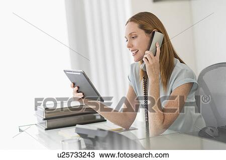 Business woman using phone and tablet pc in office View Large Photo Image Stock Image - Business woman using phone and tablet pc in office. Fotosearch