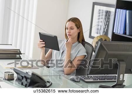Stock Photography - Business woman using tablet pc in office. Fotosearch