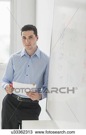Businessman standing next to whiteboard View Large Photo Image Stock Image - Businessman standing next to whiteboard. Fotosearch