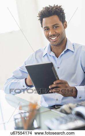 Picture - Businessman using tablet PC in office. Fotosearch