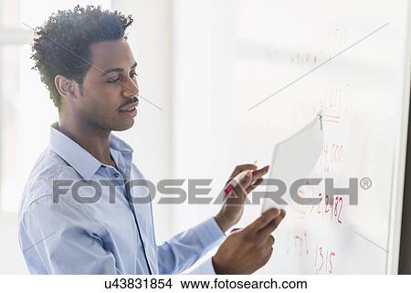 Picture - Businessman writing on whiteboard. Fotosearch