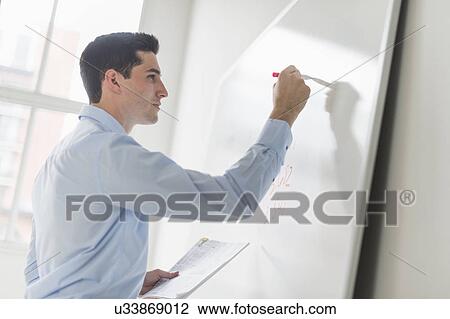 Stock Image - Businessman writing on whiteboard. Fotosearch